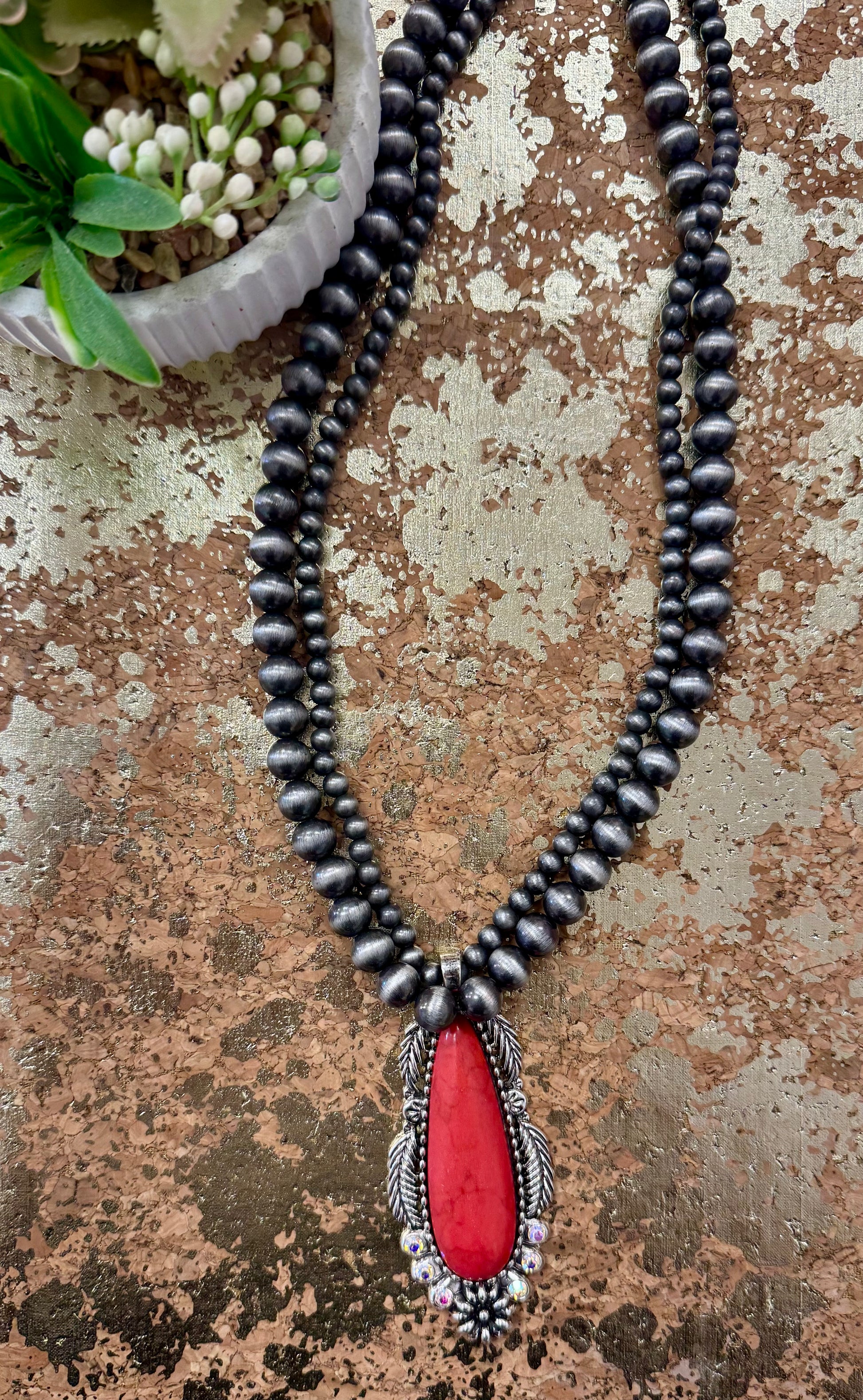 Necklace with black beads and a red pendant on a textured surface